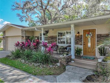 Inviting front porch with stone accents, a cozy seating area, and a beautifully crafted wooden door at 14350 11Th St, Dade City, FL 33523