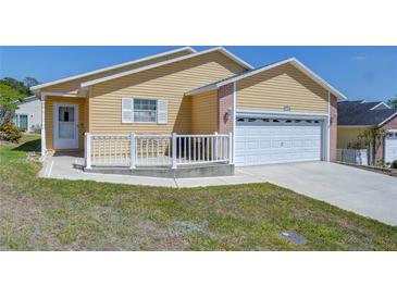 Charming single-story home with yellow siding, a white garage door, and a small front porch at 5906 Greenbriar Ct, Zephyrhills, FL 33542