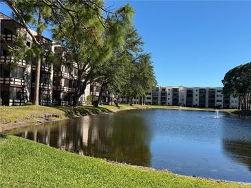 Scenic view of the community pond surrounded by lush landscaping and multi-story condo buildings on a sunny day at 5980 80Th St N # 106, St Petersburg, FL 33709