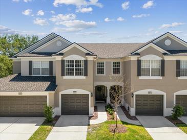 Charming townhome with attached garage and landscaped front yard, offering a welcoming curb appeal under a sunny sky at 6910 Rock Springs Way, Tampa, FL 33625