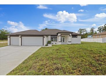 Beautiful single-story home featuring a three-car garage, modern design, and well-maintained landscaping at 7372 Madrid Rd, Weeki Wachee, FL 34613