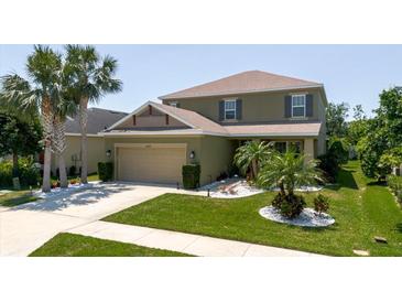 Charming two-story home featuring a well-manicured lawn, palm trees, and an attached two-car garage at 27094 Carolina Astor, Wesley Chapel, FL 33544