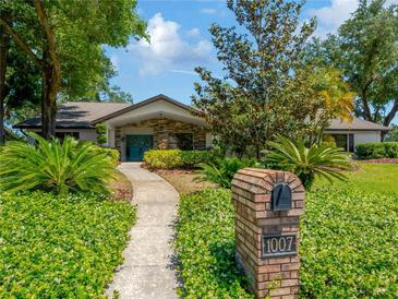 Charming single-story home featuring a well-manicured lawn, mature trees, and a welcoming walkway to a decorative front door at 1007 Morfield Ln, Brandon, FL 33511