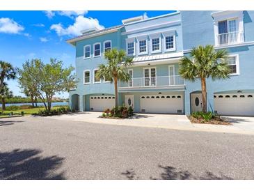 Beautiful three-story condo with an attached garage and a balcony that overlooks the waterfront and palm trees at 1134 Starfish Ln, Tarpon Springs, FL 34689