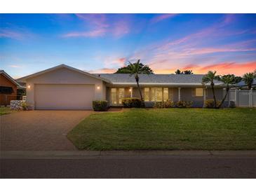 Charming single-story home with well-manicured lawn, brick driveway, and attached two-car garage at sunset at 4433 38Th S Way, St Petersburg, FL 33711