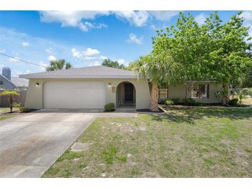 Charming single-story home featuring a two-car garage, arched entryway, and mature landscaping under a sunny sky at 5263 Kirkwood Ave, Spring Hill, FL 34608