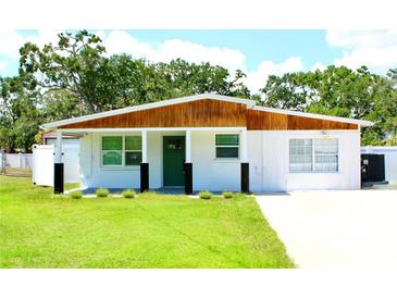 Charming single-story home with a well-maintained lawn, white paint, and a wood-accented roof and green front door at 8817 Audrey Ln, Tampa, FL 33615
