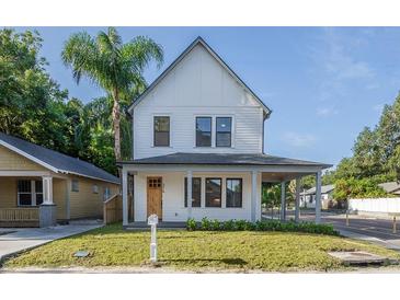 Charming two-story home with a covered front porch, a manicured lawn, and a bright exterior paint at 1230 E Emma St, Tampa, FL 33603