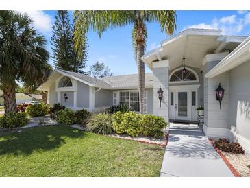 Inviting exterior view of a single-story home with manicured lawn and lush tropical landscaping at 13528 Woodside Dr, Hudson, FL 34667