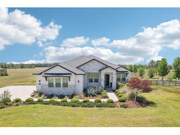 Beautiful one-story home featuring stone accents, manicured landscaping, and a lush green lawn at 32860 Drake Estates Way, Dade City, FL 33525