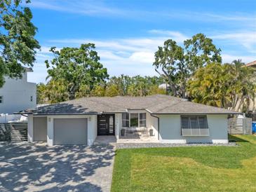 Charming single story home featuring manicured lawn, modern design, and brick paved driveway, with a covered front porch at 349 Belleair Ne Dr, St Petersburg, FL 33704