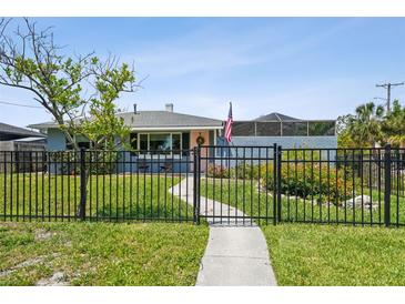 Charming, blue one story house features a tidy front yard, and black metal fence at 4013 W Waterman Ave, Tampa, FL 33609