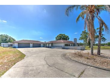 Sprawling ranch home boasts a circular driveway, neutral paint, and a spacious three-car garage at 6709 W Knights Griffin Rd, Plant City, FL 33565