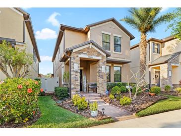 Charming two-story home featuring a stone-accented porch and a well-maintained lawn with lush landscaping at 28638 Tranquil Lake Cir, Wesley Chapel, FL 33543