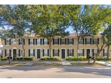Charming townhomes featuring black shutters, well-manicured landscaping, and mature trees at 9534 W Park Village Dr, Tampa, FL 33626