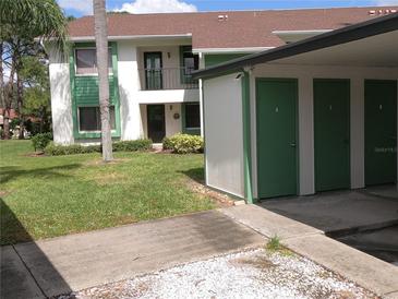Condominium building with green storage unit and green trim, surrounded by lush lawn and trees at 2555 Royal Pines Cir # A, Clearwater, FL 33763