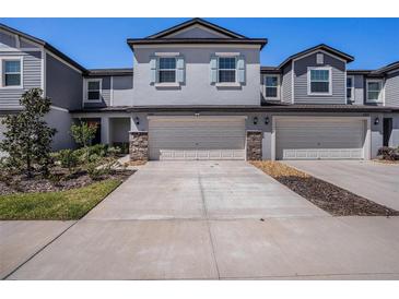 Charming townhome featuring a two-car garage and stone-accented columns enhancing its curb appeal at 32091 S Pop Ash N Pl, San Antonio, FL 33576