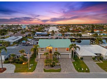 Beautiful aerial view of a coastal home with a green roof, canal access, and picturesque sunset at 3505 Seaway Dr, New Port Richey, FL 34652