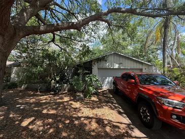 Modest single Gathering home with mature shade trees and an orange pickup truck in the driveway at 5517 Pentail Cir, Tampa, FL 33625