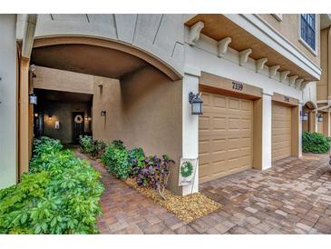 Garage of the townhome with landscaping and a welcome sign near the front door and paver driveway at 7339 Skybird Rd # 7339, Bradenton, FL 34209