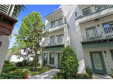 Charming multi-story condo with white exterior, green trim, and balconies overlooking landscaped grounds at 946 Highland Ave # 47, Dunedin, FL 34698