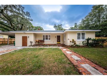 Charming single-story home boasts a lush front lawn, brick pathway, and inviting porch swing at 1205 E Hamilton Ave, Tampa, FL 33604