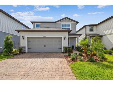 Charming two-story home featuring a gray exterior, brick driveway, and manicured landscaping at 17652 Ramble On Way, Land O Lakes, FL 34638