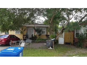 Modest single-story home with a fenced front yard and mature trees providing shade at 2542 Irving S Ave, St Petersburg, FL 33712