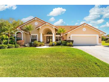 Inviting single-story home featuring a well-manicured lawn, a terracotta roof, and a covered entryway with classic architectural details at 30314 Fairway Dr, Wesley Chapel, FL 33543