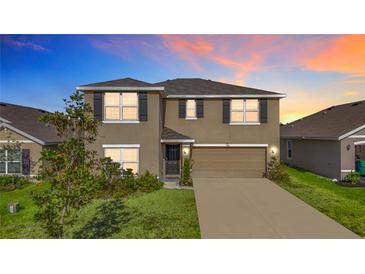 Inviting two-story home boasts a well-manicured lawn, attached garage, and classic architectural details at 7782 Sail Clover Ln, Zephyrhills, FL 33540
