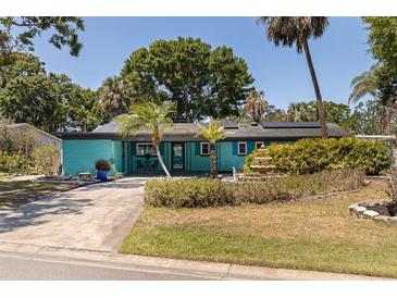 Charming turquoise home featuring lush landscaping, solar panels, and a welcoming front patio at 8401 Stillbrook Ave, Tampa, FL 33615