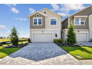 Two-story home featuring a paver driveway, two-car garage, manicured lawn, and neutral color scheme at 10712 Oak Bend Dr, Parrish, FL 34219