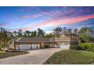 Stunning two-story home with a brick driveway and a three-car garage, offering ample parking and curb appeal at 11296 Warm Wind Way, Weeki Wachee, FL 34613