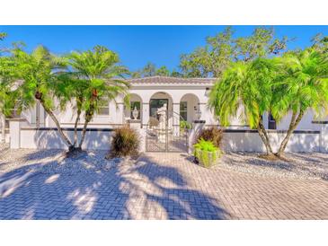 Charming two-story home with lush palm trees, manicured garden beds, and a brick paver driveway at 13483 Heritage Way, Sarasota, FL 34240