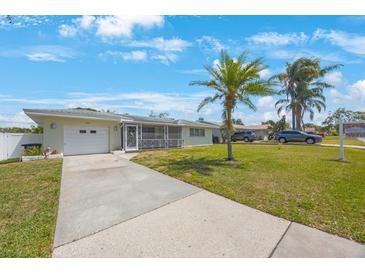 Charming single-story home featuring a one-car garage, screened porch, and well-maintained lawn under a bright blue sky at 1410 Lime St, Clearwater, FL 33756