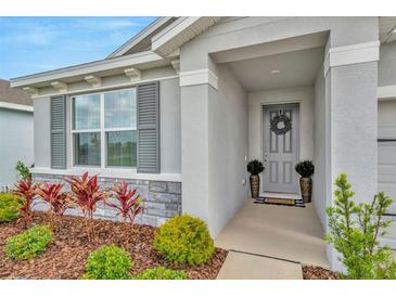 Inviting front entrance with a gray door, decorative wreath, and well-maintained landscaping at 3504 Golden Wheat Ln, Plant City, FL 33565