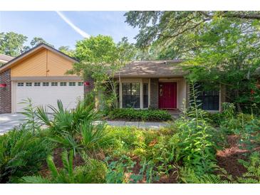 Charming home with mature landscaping, brick accents, and a vibrant red front door at 4215 Water Oaks Ln, Tampa, FL 33618
