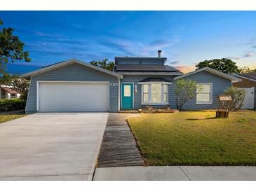Charming single-story home with a well-manicured lawn, garage and blue door at 7025 Orkney N Ave, St Petersburg, FL 33709