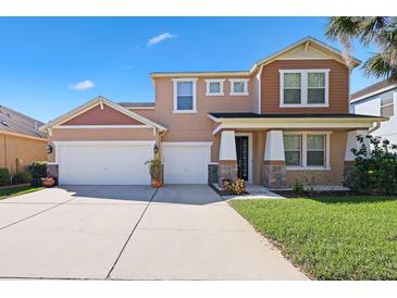 Two-story stucco home featuring an attached three-car garage and a well-manicured lawn in a suburban neighborhood at 15608 Starling Water Dr, Lithia, FL 33547