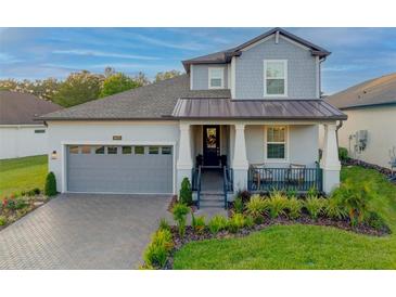 Charming two-story home featuring a covered porch, gray brick driveway, and a manicured lawn at 19475 Bristol Wood Pl, Brooksville, FL 34601