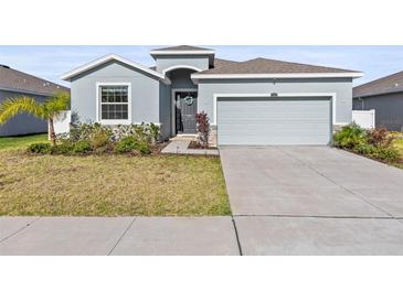 A single Gathering home with a two-car garage, a manicured lawn and stone accents at 7139 Steer Blade Dr, Zephyrhills, FL 33541