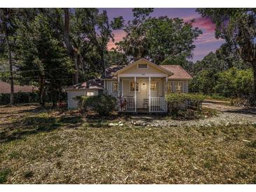 Charming single-story home featuring a cozy front porch surrounded by lush landscaping and mature trees at 11101 Corlett Rd, Riverview, FL 33578