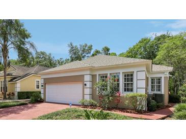 Side view of single-story home featuring a white garage door, brick driveway and well-maintained landscaping at 15324 Sherwood Forest Dr, Tampa, FL 33647