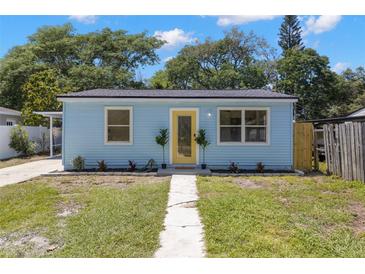Charming light blue home featuring a freshly landscaped front yard and vibrant yellow front door at 1974 N Betty Ln, Clearwater, FL 33755