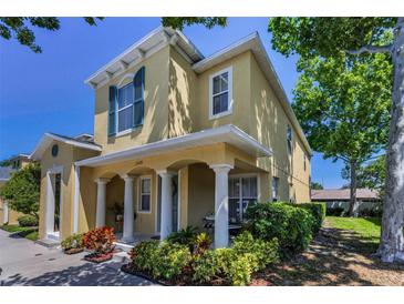 Charming two-story home featuring a covered front porch with decorative columns and lush landscaping at 2574 Hidden Cove Ln, Clearwater, FL 33763