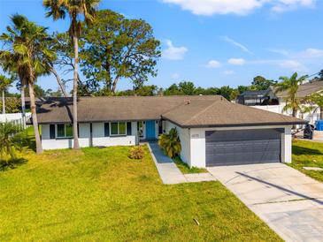 Charming single-story home with a two-car garage, blue front door, and beautifully landscaped front yard at 6070 Denver Ne St, St Petersburg, FL 33703