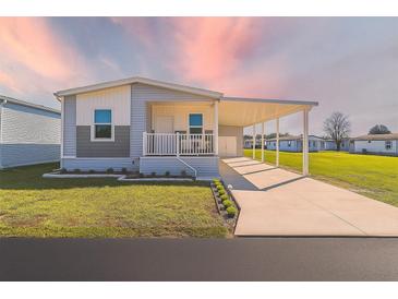 Inviting single-story home with a covered carport and a well-manicured lawn with beautiful sunset at 10029 Wellington Ave, Dade City, FL 33525