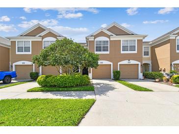 Inviting two-story townhome featuring a two-car garage, manicured lawn, and lush shrubbery at 10135 Post Harvest Dr, Riverview, FL 33578