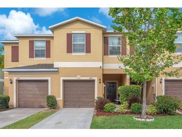 Inviting townhome featuring a well-maintained lawn, a two-car garage, and charming curb appeal at 12913 Dream Catcher Way, Riverview, FL 33579