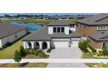 Beautiful two-story home with a three-car garage, lush landscaping, and serene water view at 13246 Twin Bridges Dr, Riverview, FL 33579